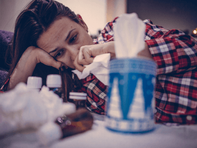 woman in pajamas sick in bed with tissues- mold in hvac system affect indoor air quality
